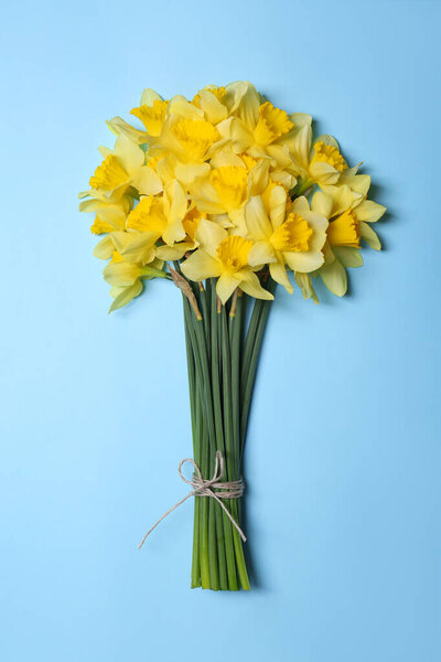 Bouquet of beautiful yellow daffodils on light blue background, top view