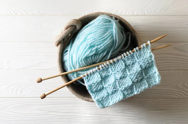 柔らかいターコイズ糸 編み物と白い木製のテーブルの針 トップビュー — ストック写真