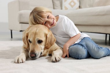 Evinde yerde Golden Retriever 'ı olan sevimli küçük bir çocuk. Sevimli hayvan.