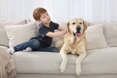 Evdeki kanepesinde Labrador Retriever 'ı olan sevimli bir çocuk. Sevimli hayvan.