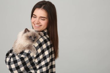 Açık gri arka planda sevimli kedisi olan mutlu kadın, mesaj için yer var.