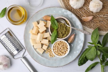 Lezzetli pesto sosu ve beyaz desenli masa üzerindeki malzemeler.