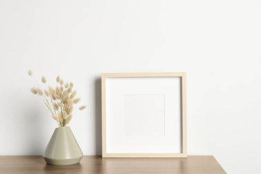 Boş fotoğraf çerçevesi ve vazo. Ahşap masa üzerinde kuru dekoratif çiviler. Tasarım için model