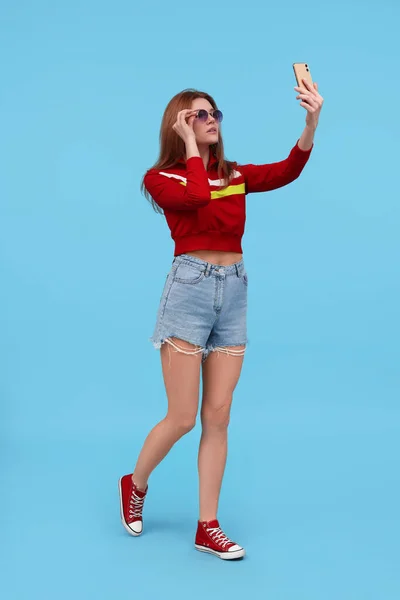 Schöne Frau Mit Sonnenbrille Macht Selfie Auf Hellblauem Hintergrund — Stockfoto