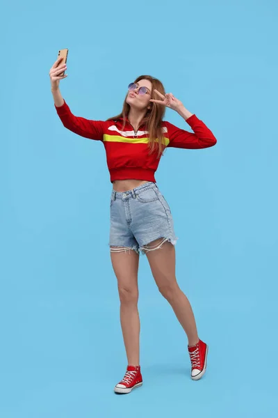 Schöne Frau Mit Sonnenbrille Macht Selfie Auf Hellblauem Hintergrund — Stockfoto