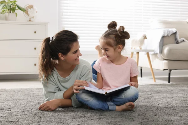 年轻的母亲和她的女儿在家里的地板上看书 — 图库照片
