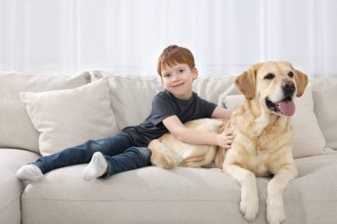 Evdeki kanepesinde Labrador Retriever 'ı olan sevimli bir çocuk. Sevimli hayvan.