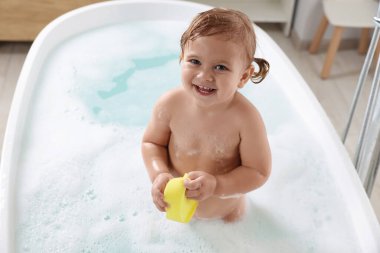 Süngerli şirin küçük kız evde köpüklü banyo yapıyor.