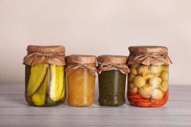 Ahşap masada farklı malzemelerle korunmuş kavanozlar.