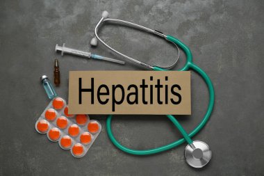 Üzerinde kelime hepatit ve tıbbi malzeme olan karton gri masa, düz yatıyordu.