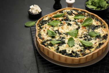 Lezzetli ev yapımı ıspanaklı kiş siyah masada, yakın plan.