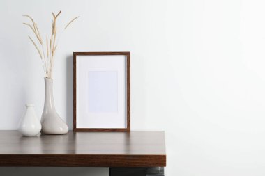 Boş fotoğraf çerçevesi ve vazo. Ahşap masa üzerinde kuru dekoratif çiviler. Tasarım için model