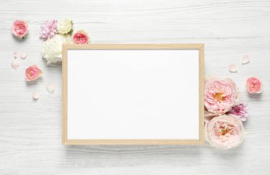 Boş fotoğraf çerçevesi ve beyaz ahşap masa üzerinde güzel çiçekler. Tasarım için boşluk