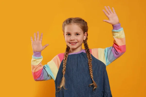 Ευτυχισμένο Κορίτσι Δίνει Κόλλα Πέντε Και Δύο Χέρια Πορτοκαλί Φόντο — Φωτογραφία Αρχείου