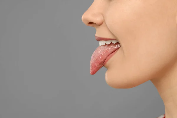 灰色の背景に彼女の舌を示す幸せな若い女性 クローズアップ テキストのスペース — ストック写真
