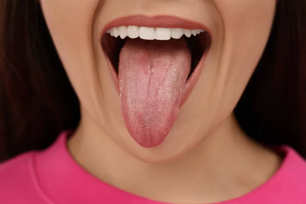 快乐的年轻女子在粉红的背景上露出舌头 — 图库照片