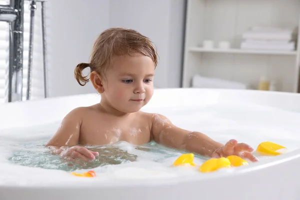 可爱的小女孩带着橡胶鸭在家里泡泡浴 — 图库照片