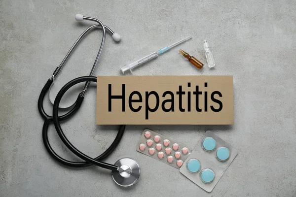 stock image Cardboard with word Hepatitis and medical supplies on light grey table, flat lay