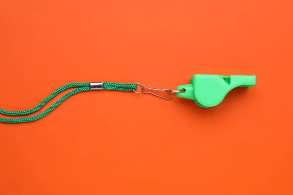 stock image One green whistle with cord on orange background, top view