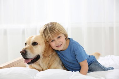 Evde yatağında Golden Retriever olan sevimli küçük bir çocuk. Sevimli hayvan.
