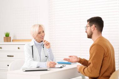 Klinikteki beyaz masada danışmanlık yapan bir doktor.