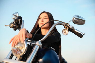 Beautiful young woman sitting on motorcycle outdoors