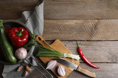 Ratatouille pişiriyorum. Sebzeler, biberiye ve bıçak ahşap masada, düzlük ve metin için yer var.