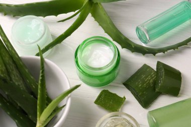 Farklı kozmetik ürünleri ve beyaz ahşap masa üzerinde aloe vera yaprakları kesimi