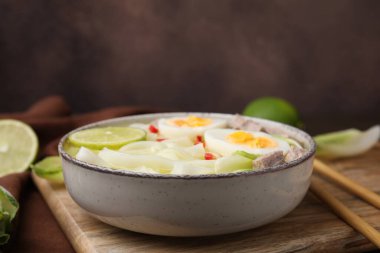 Bir kase lezzetli pirinç eriştesi çorbası et ve yumurta tahtada, yakın plan.