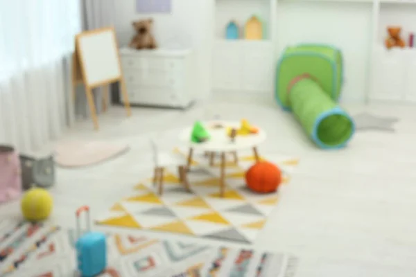 不同的玩具和家具模糊了儿童游戏室的景观 雅致的幼稚园内部 — 图库照片