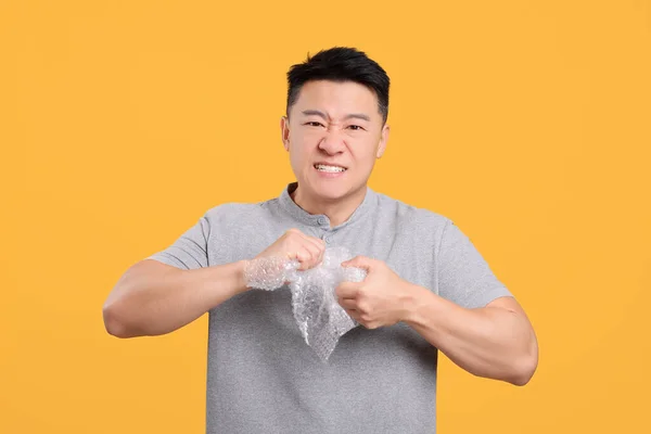 Emotionele Aziatische Man Met Bubble Wrap Oranje Achtergrond — Stockfoto