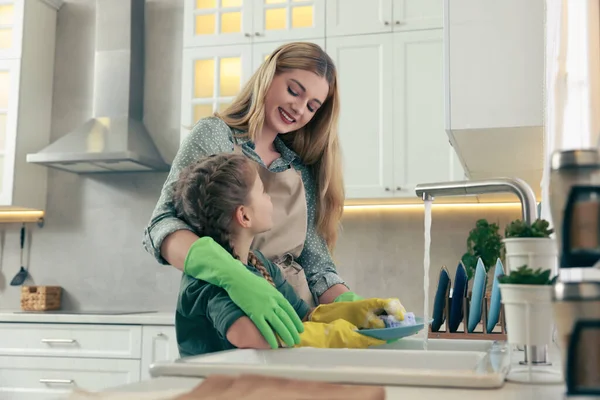 母亲和女儿戴着防护手套 在厨房的洗碗槽上洗盘子 — 图库照片
