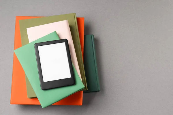 stock image Modern e-book reader and stack of hard cover books on light grey table, top view. Space for text