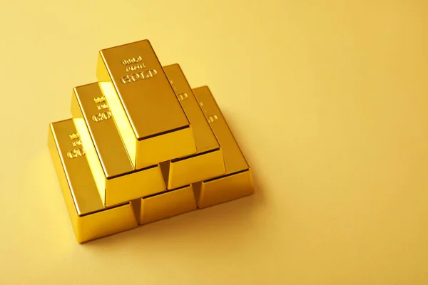 stock image Stack of shiny gold bars on yellow background. Space for text