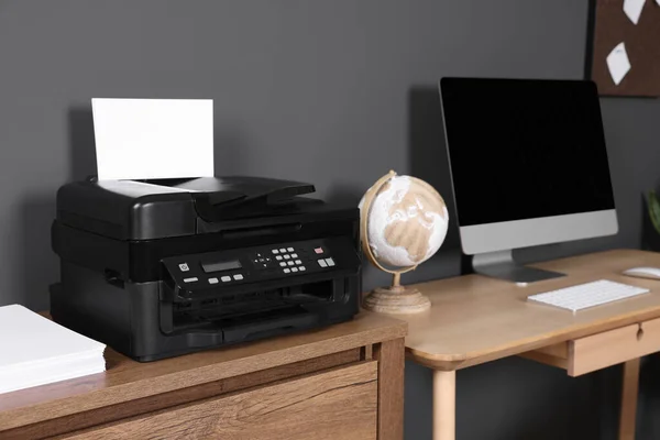 自宅で木製の机の上にコンピュータの近くに紙と現代のプリンタ — ストック写真