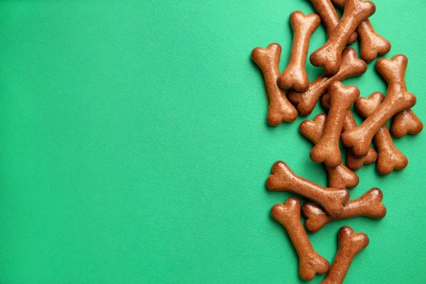 stock image Bone shaped dog cookies on green background, flat lay. Space for text