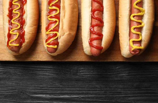 Deliciosos Cachorros Quentes Com Mostarda Ketchup Mesa Madeira Preta Vista — Fotografia de Stock