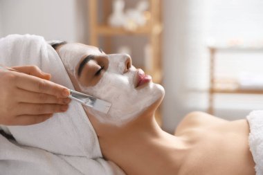 Kaplıca salonunda kadının yüzüne maske takan kozmetikçi.