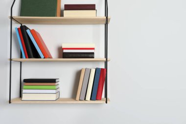 Beyaz duvarda bir sürü ciltli kitap olan raflar. Metin için boşluk