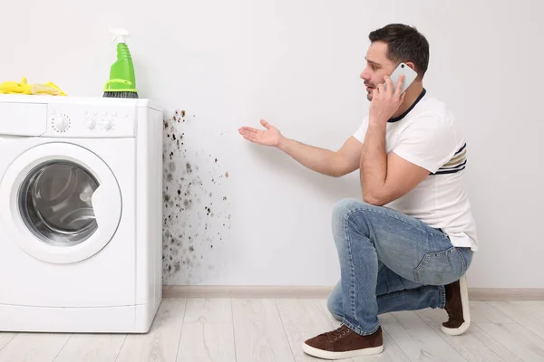 Schimmelbeseitigungsservice Mann Telefoniert Und Sieht Betroffene Wand Badezimmer — Stockfoto