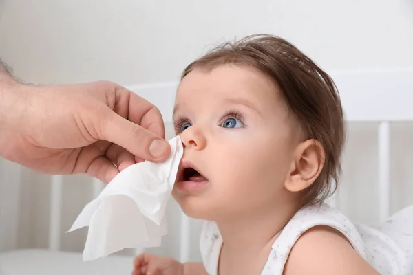 stock image Father wiping runny nose of little baby with napkin on bed, closeup