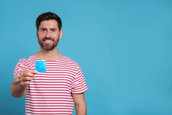 Šťastný Muž Drží Kondom Světle Modrém Pozadí Prostor Pro Text — Stock fotografie