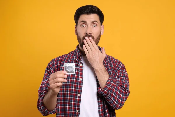 Emotional Man Holding Condom Yellow Background Safe Sex — Stock Photo, Image