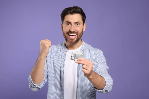 Emotional Man Holding Condoms Purple Background Safe Sex — Stock Photo, Image