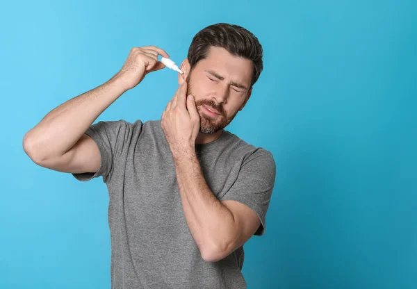 Hombre Usando Gotas Oído Sobre Fondo Azul Claro —  Fotos de Stock
