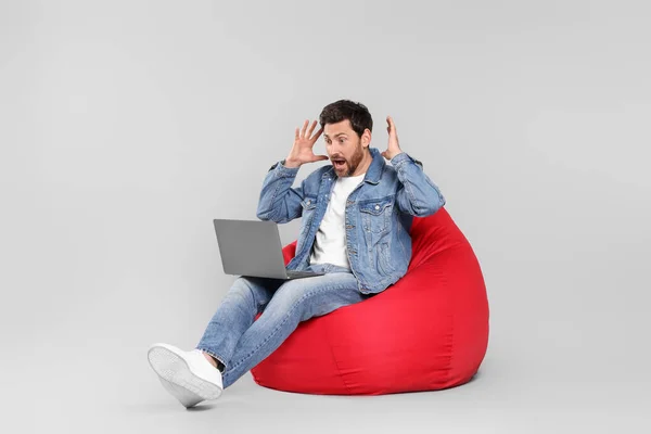 Homem Emocional Com Laptop Sentado Cadeira Beanbag Contra Fundo Cinza — Fotografia de Stock