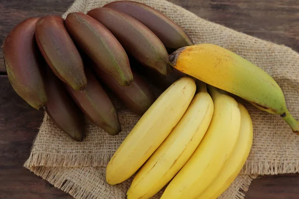 stock image Different sorts of bananas on wooden table, top view