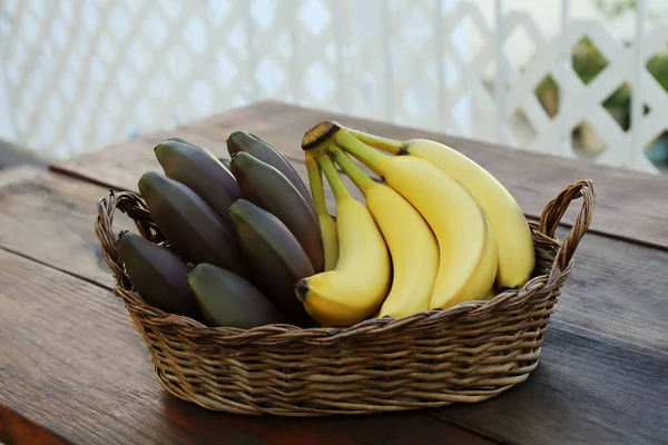 Cesta Vime Com Saborosas Bananas Roxas Amarelas Mesa Madeira — Fotografia de Stock