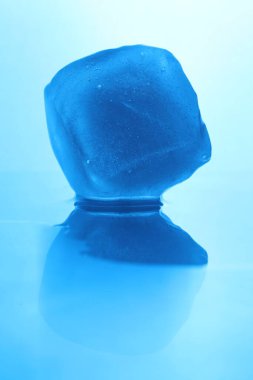 Açık mavi arka planda kristal berrak buz küpü, yakın plan. Renk tonu etkisi
