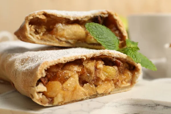 Delicious strudel with apples, nuts and raisins on marble board, closeup